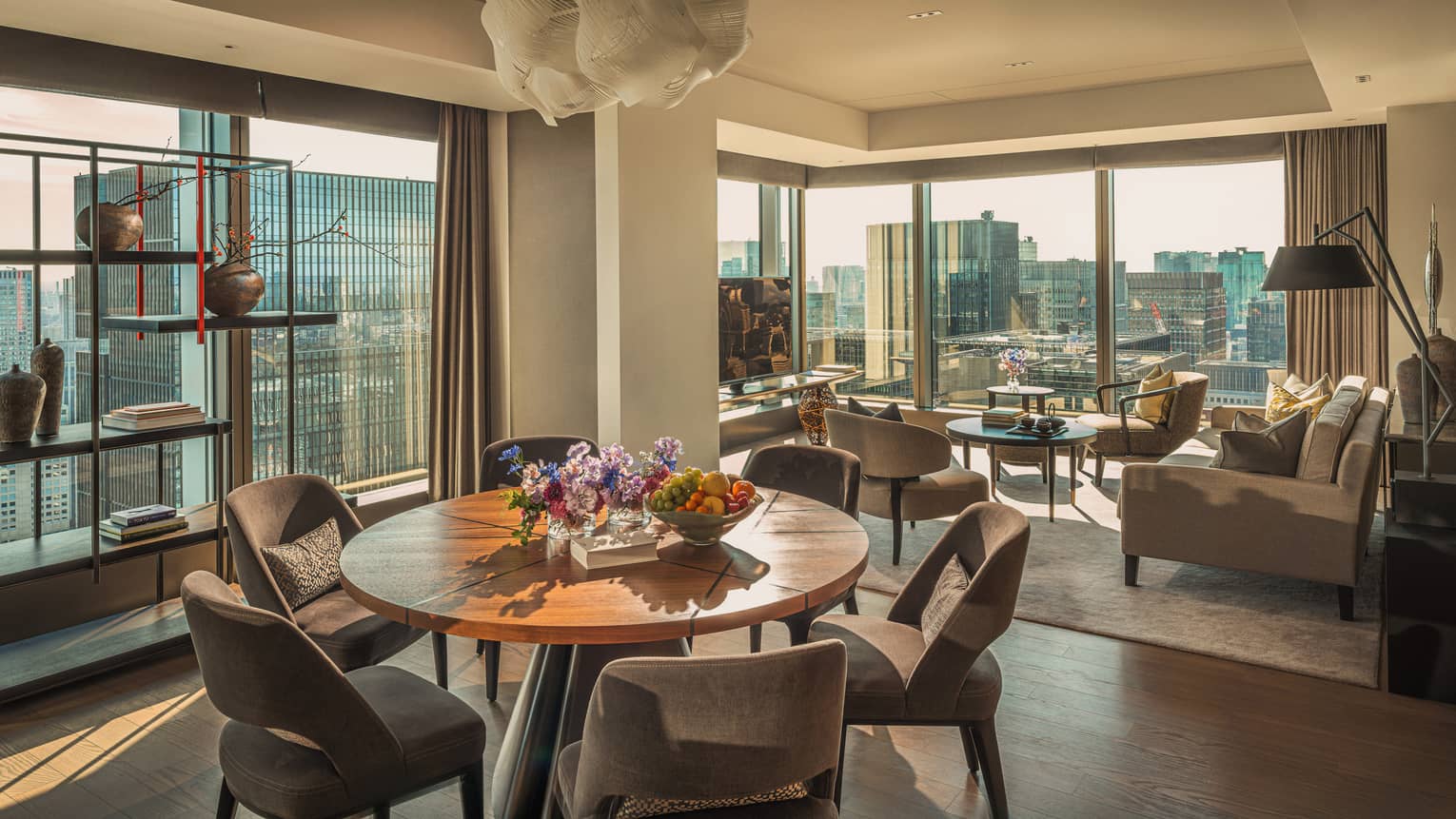 Luxury hotel suite featuring a living room and dining room with two walls of windows looking out to city view