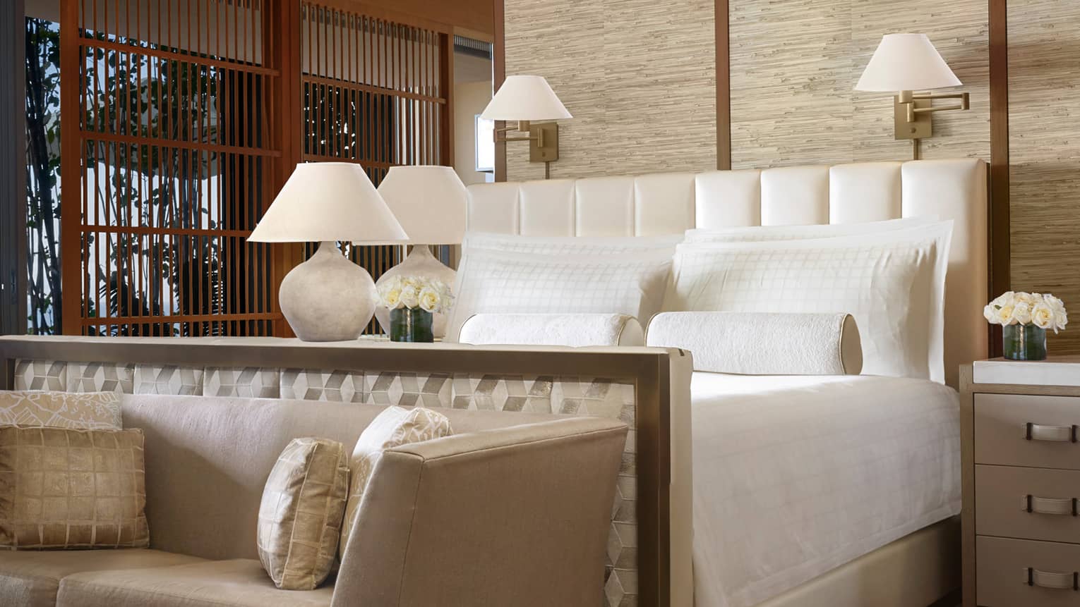 Kapihaa Presidential Suite bed, white lamp, flowers, plush chaise and pillows at foot