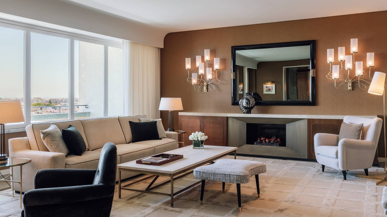 Living room with cream sofa, white arm chair, black arm chair, wall schones, brown accent wall