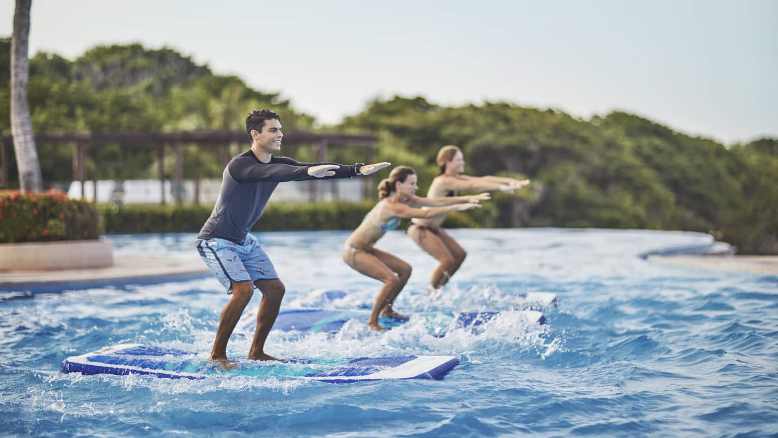 Two guests being instructed how to stand up on surf boards