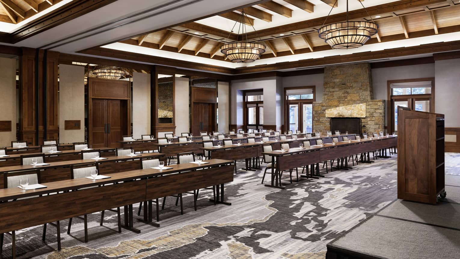 A large room with long tables and light coloured chairs, a podium and a stage.
