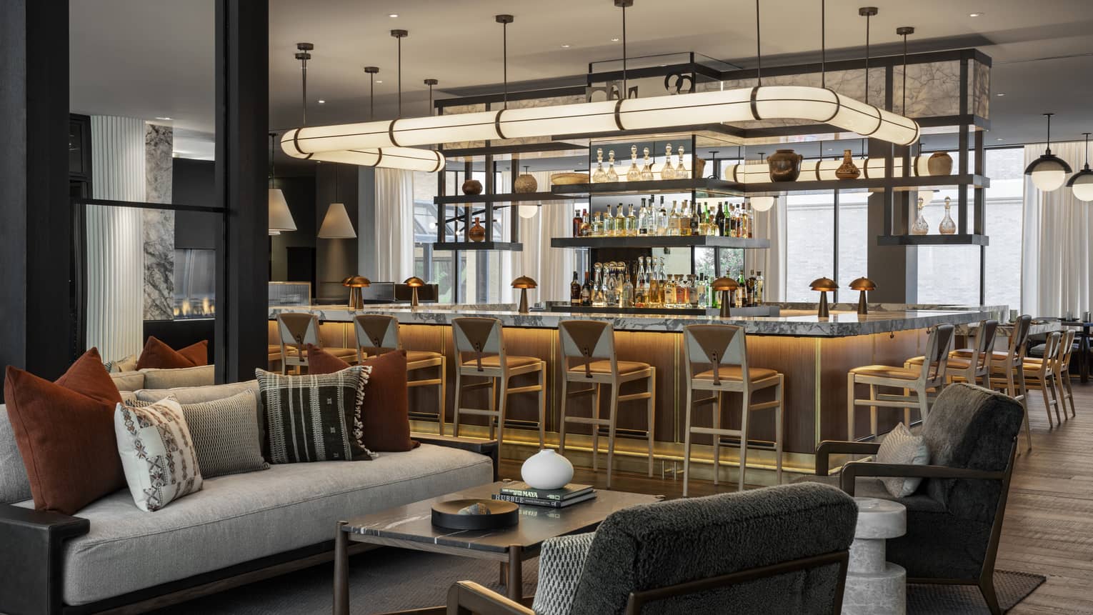 The inside of a lounge/bar area with a large tube light, stools around a bar, and hanging lights in the background.