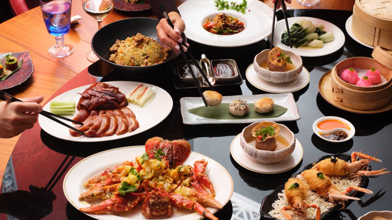 Round dining table with various dishes that people share, including meat and fried shellfish