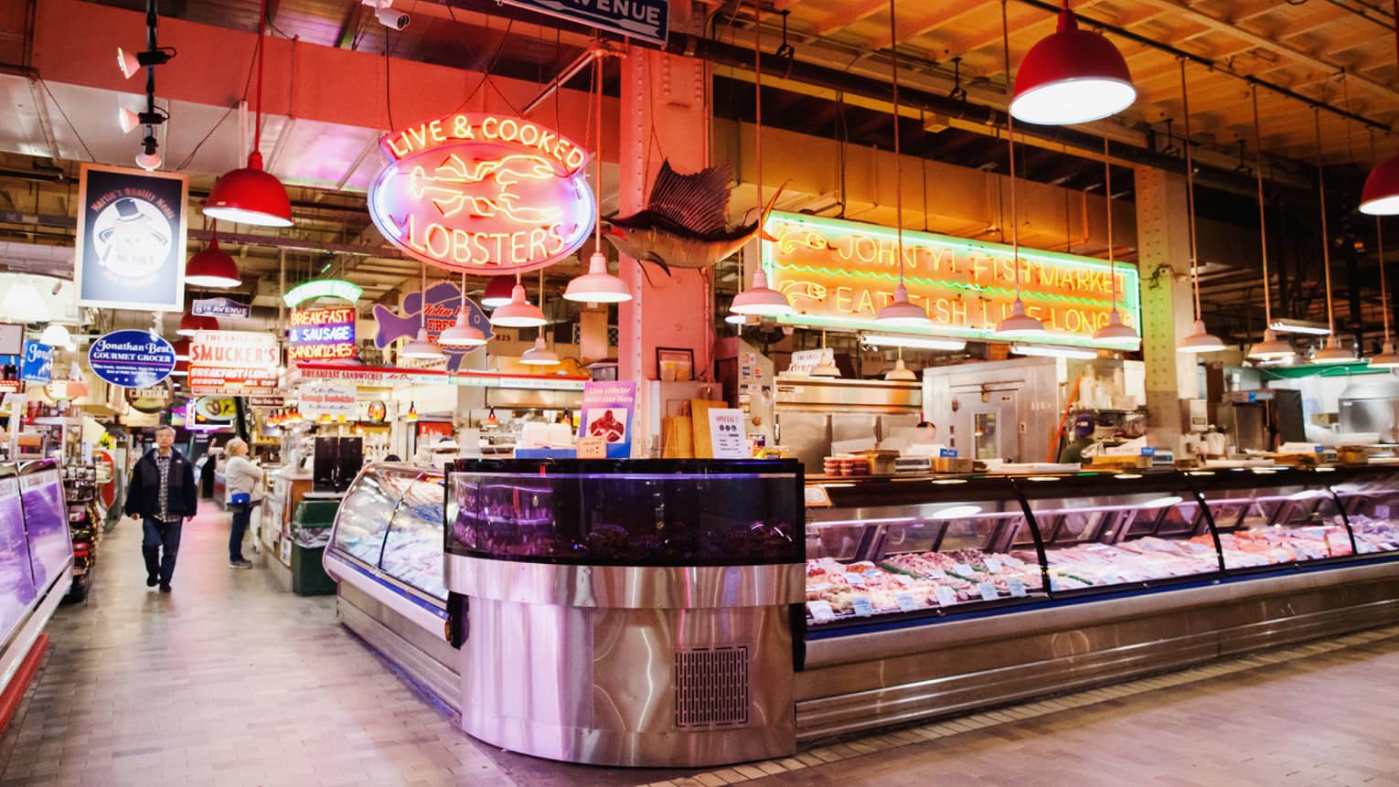A large indoor market featuring fresh seafood behind glass windows.