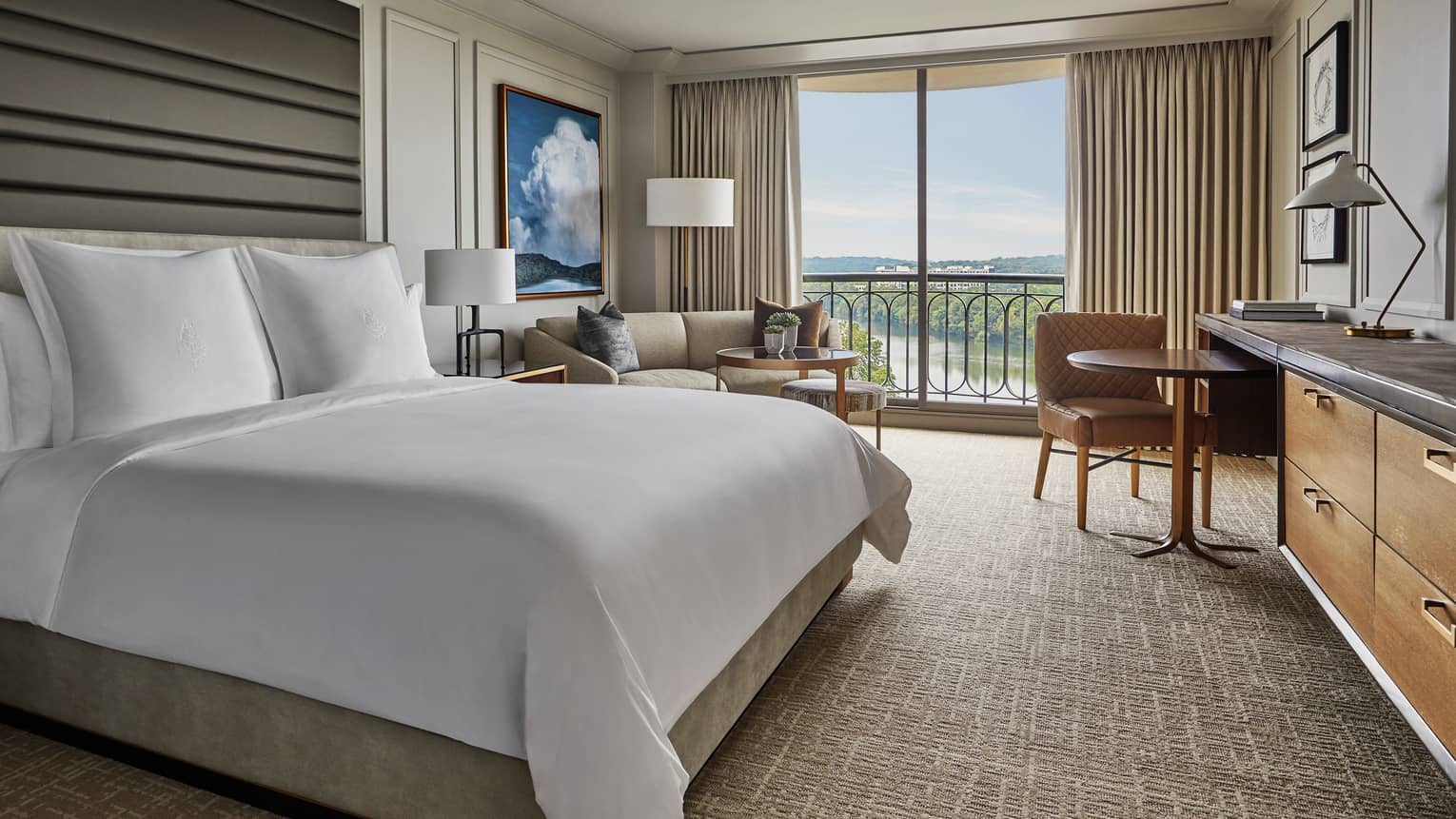 Lake View Balcony room bed, tall padded headboard, sofa, dining table by window