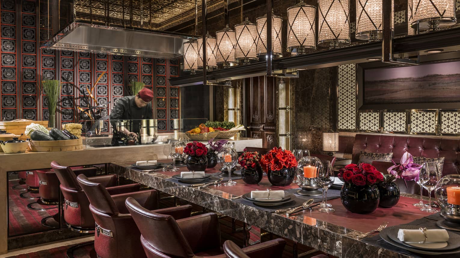 Elegant eight-person black marble Chef's Table in front of chef at open kitchen line, row of lanterns above