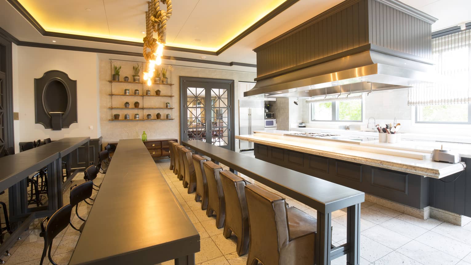 Rows of long tables and chairs face large presentation kitchen space, light fixtures made of rope