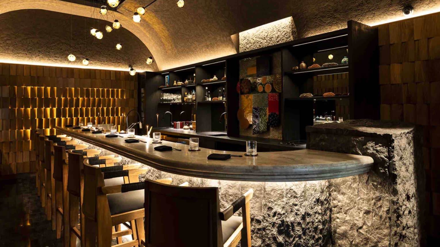 Modern, elegant interior dining space with curved ceiling, cozy lighting and a curved dining bar with tall seats