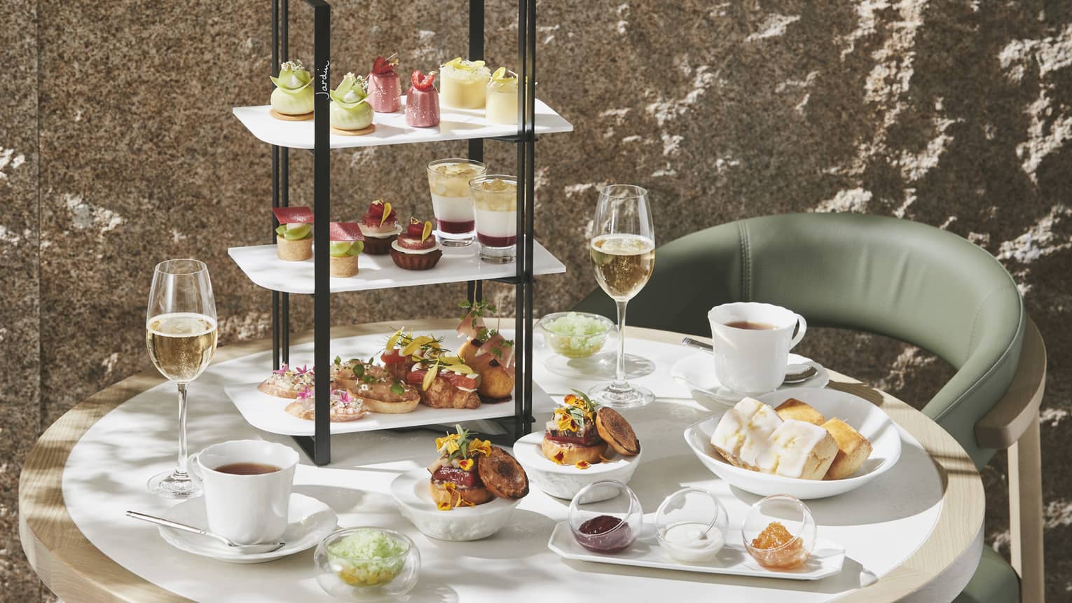 Afternoon Tea set up with three-tiered display of sweet and savoury foods, two glasses of champagne and two glasses of tea