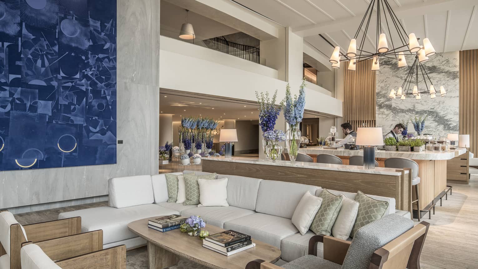 Bar and lounge featuring a white l-shaped sofa and arm chairs, with the bar set behind