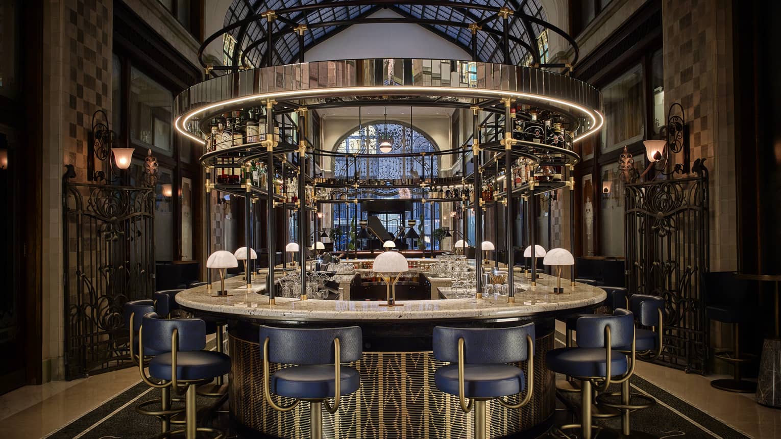 Modern bar with navy and gold bar stools, marble top, bottles around top