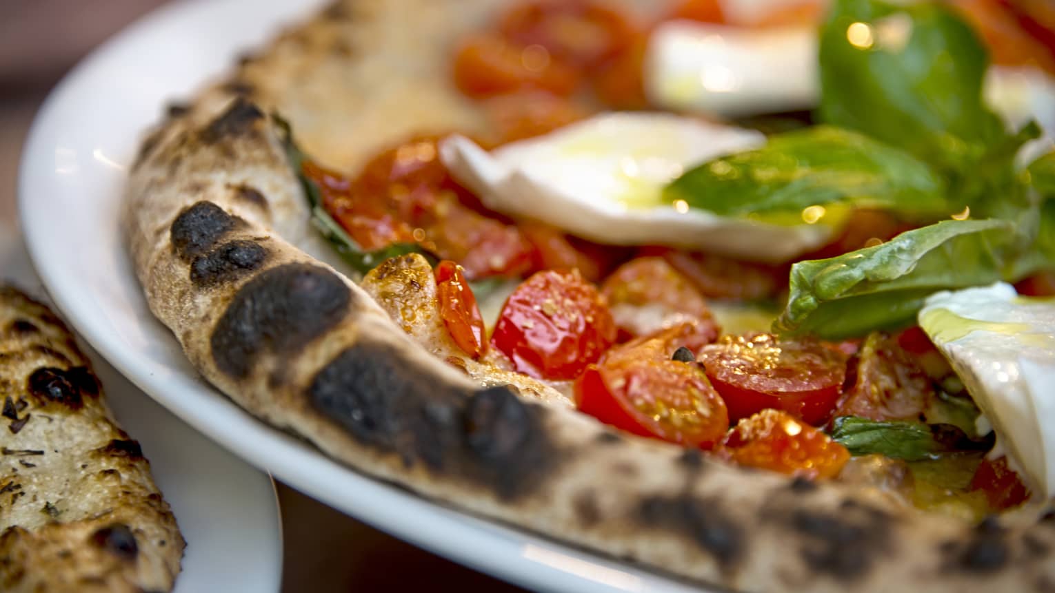 Close-up of Al Fresco signature pizza thin wheat crust, fresh cherry tomatoes, basil