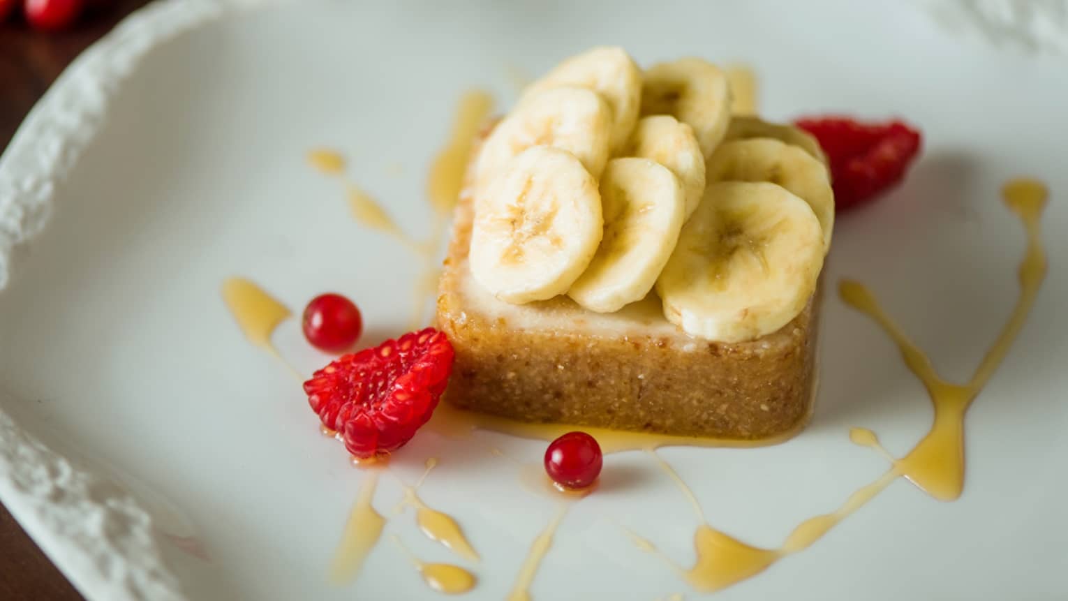 A slice of pie topped with banana and orange sauce.
