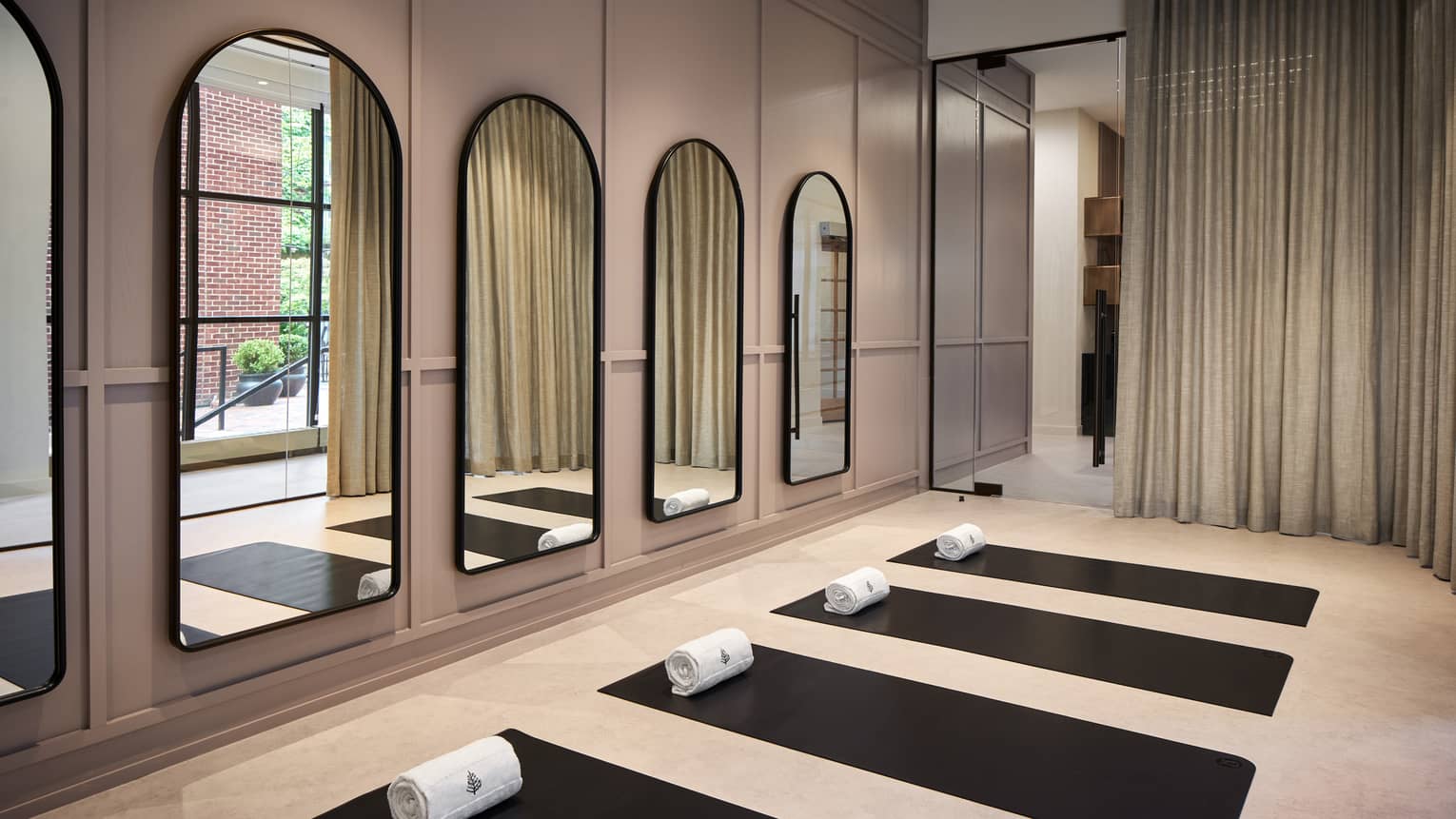 Yoga mats in a yoga studio with mirrors on the wall.