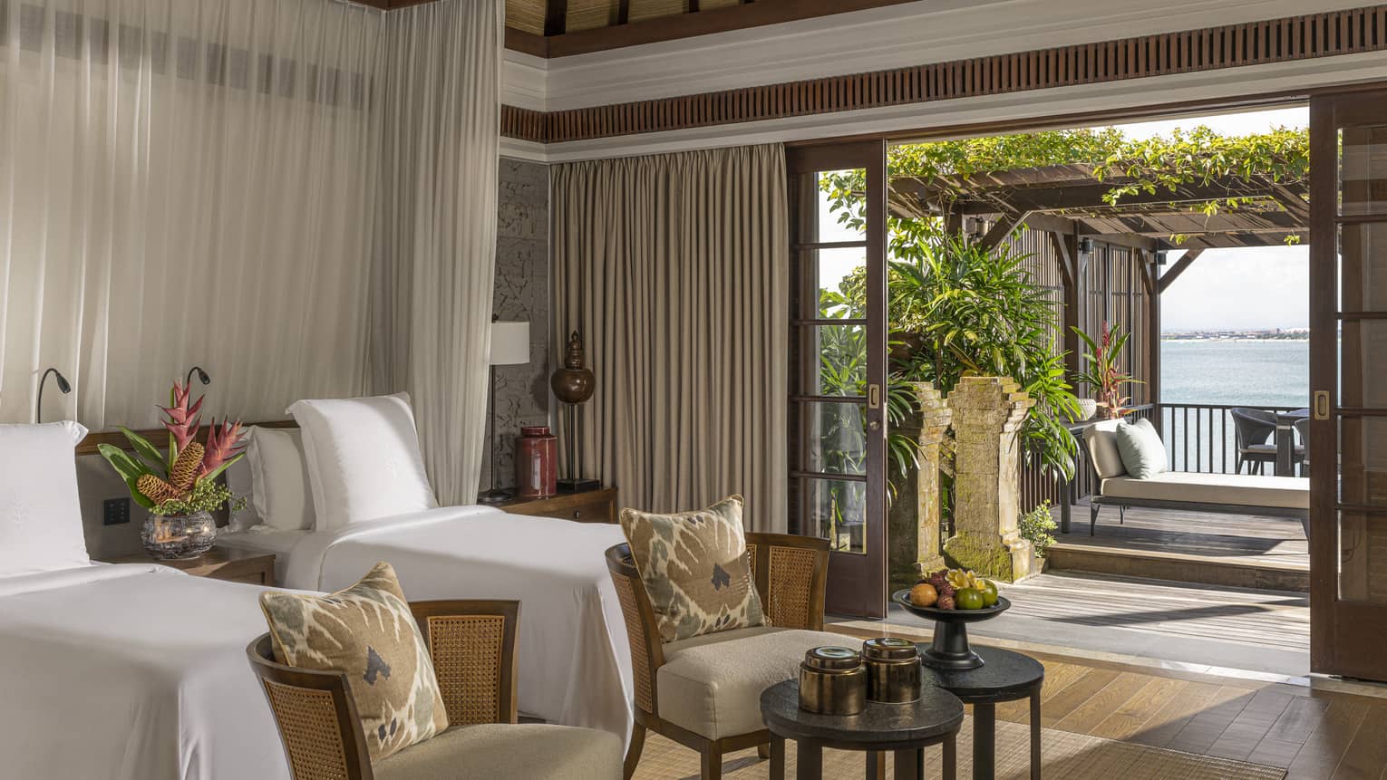 Royal Villa bedroom with double canopy beds, armchairs, doorway to pool and lounge area