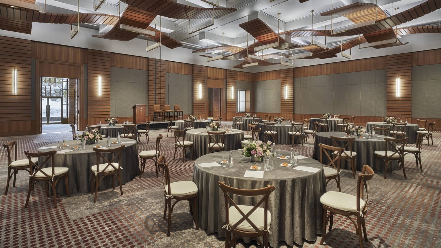 A ballroom setup with green tablecloths on circular tables.