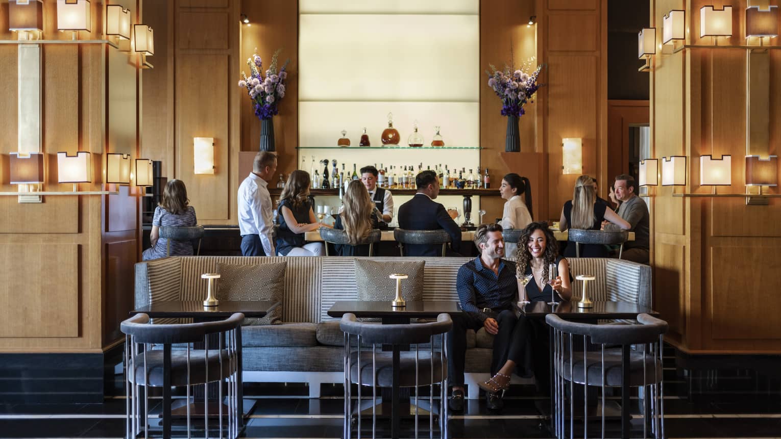 People sitting at a bar and booth in a dining outlet.