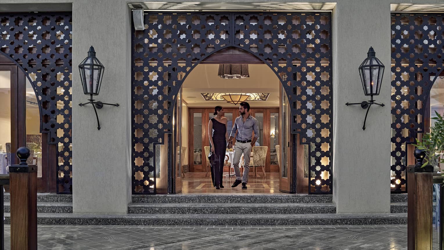 Man and woman walking out of a restaurant with Arabesque detailing around doorway