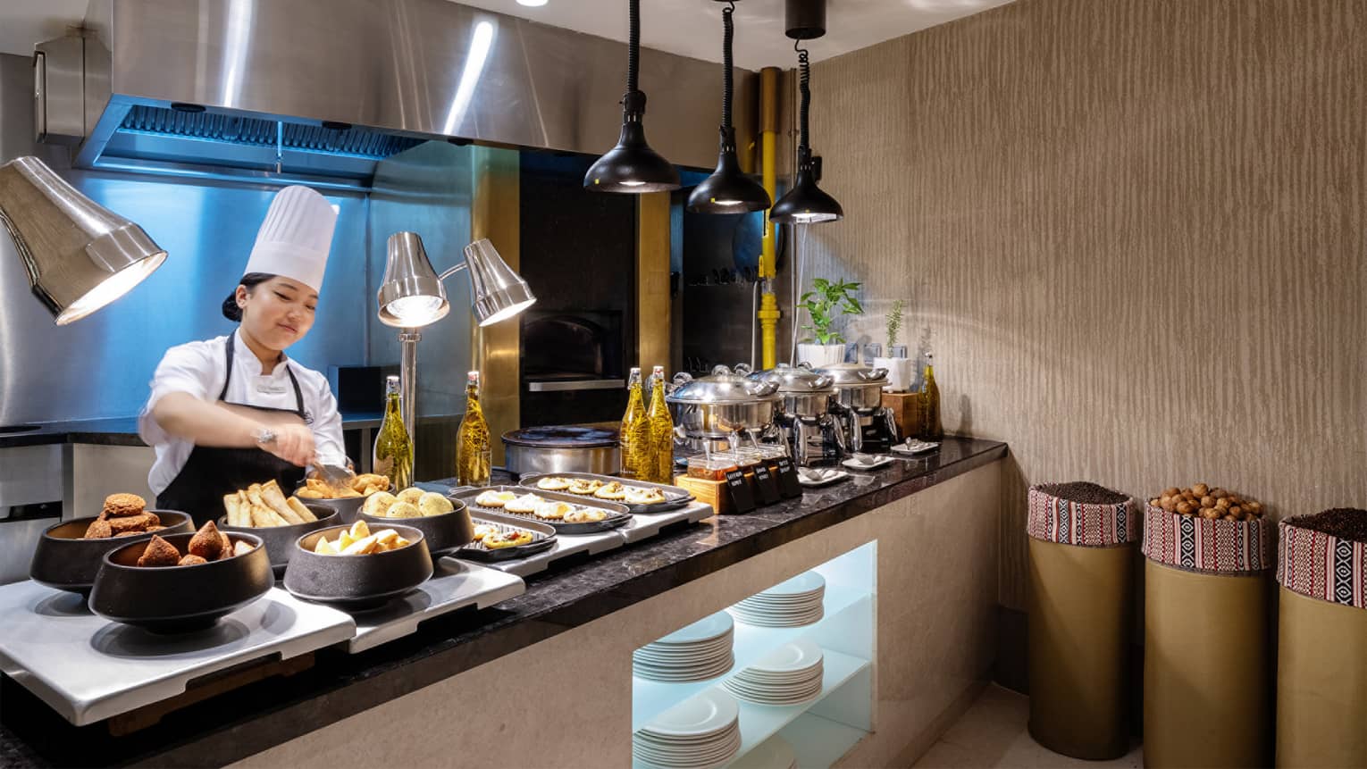 Breakfast buffet set up on a black marble counter with a chef standing behind the counter arranging items