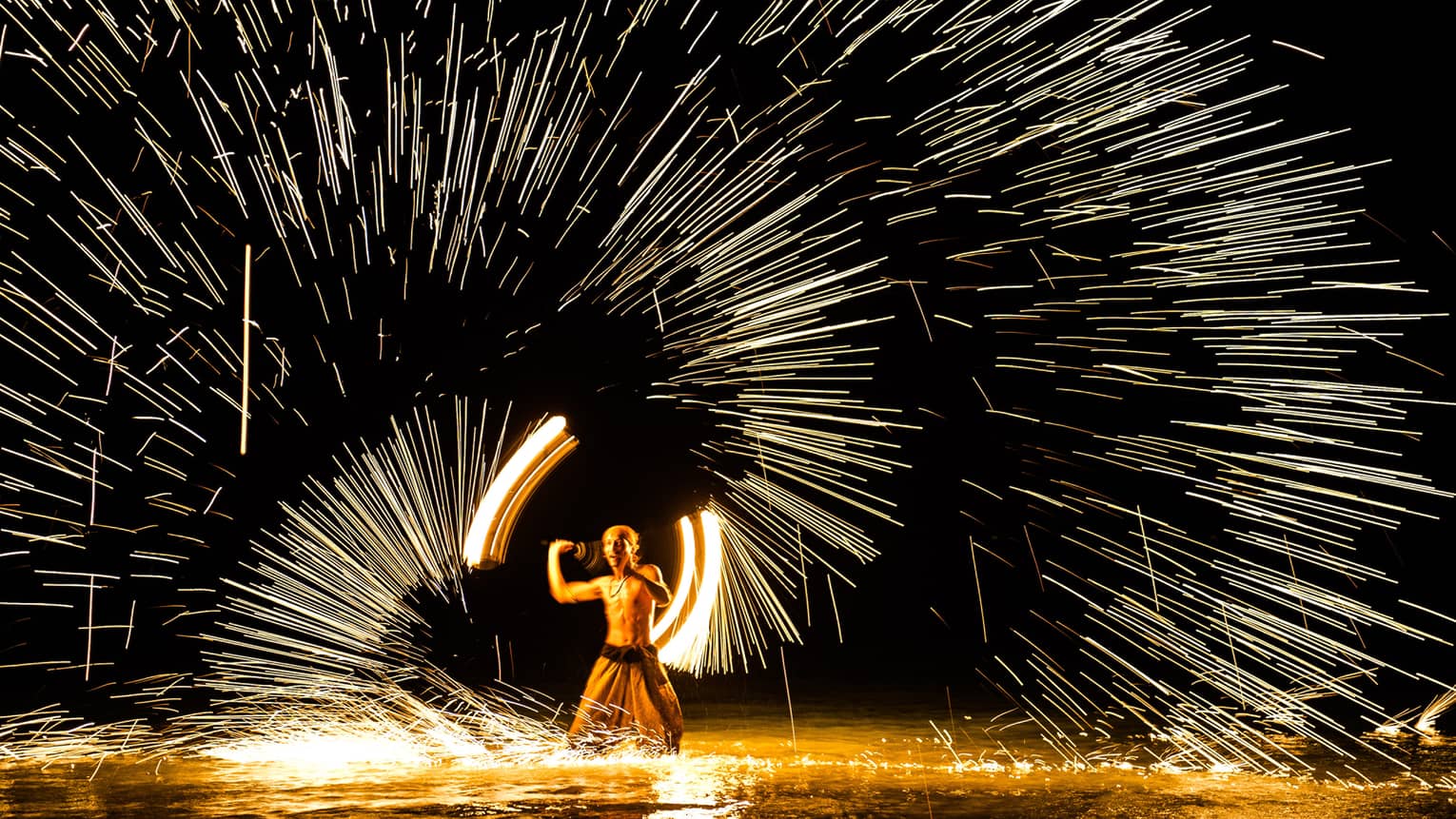 Streaks of light around man spinning fire