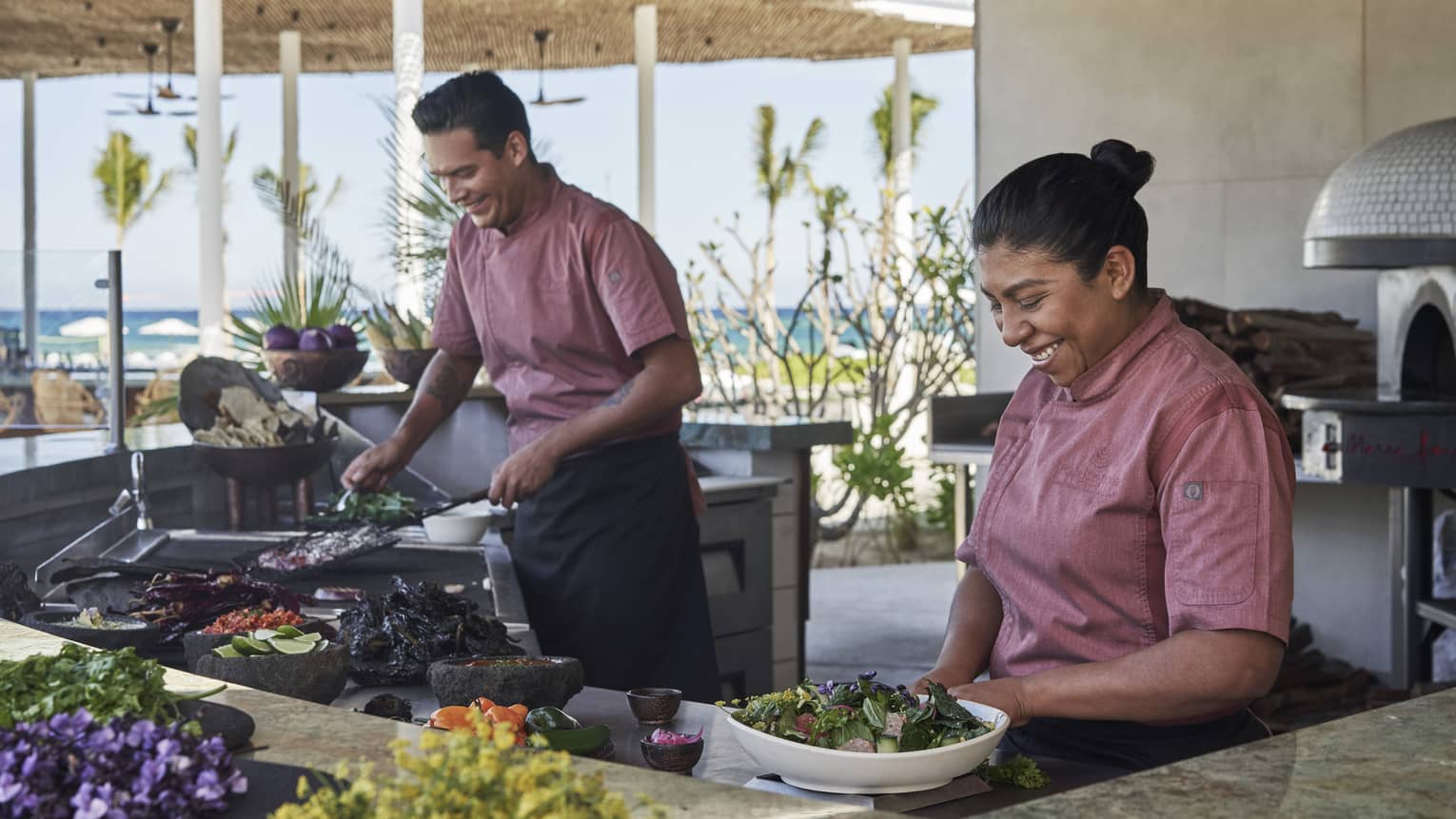 Two four seasons staff members prepare foot at the outdoor eating area of Casa de Brasa in Los Cabos