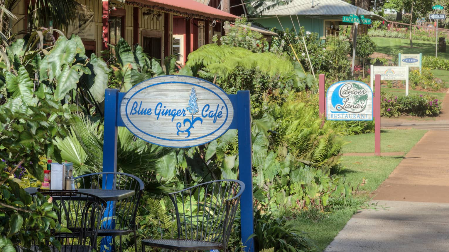 Garden patio table under Blue Ginger Cafe sign, path leading to more cafes and shops