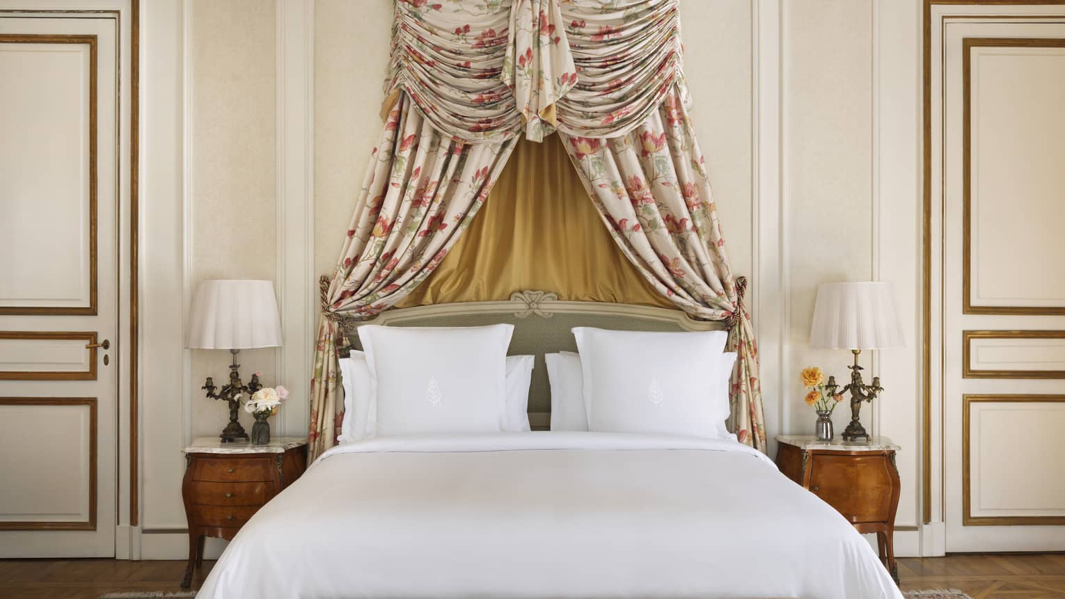 King bed with white linens and a canopy-style headboard made from floral fabric