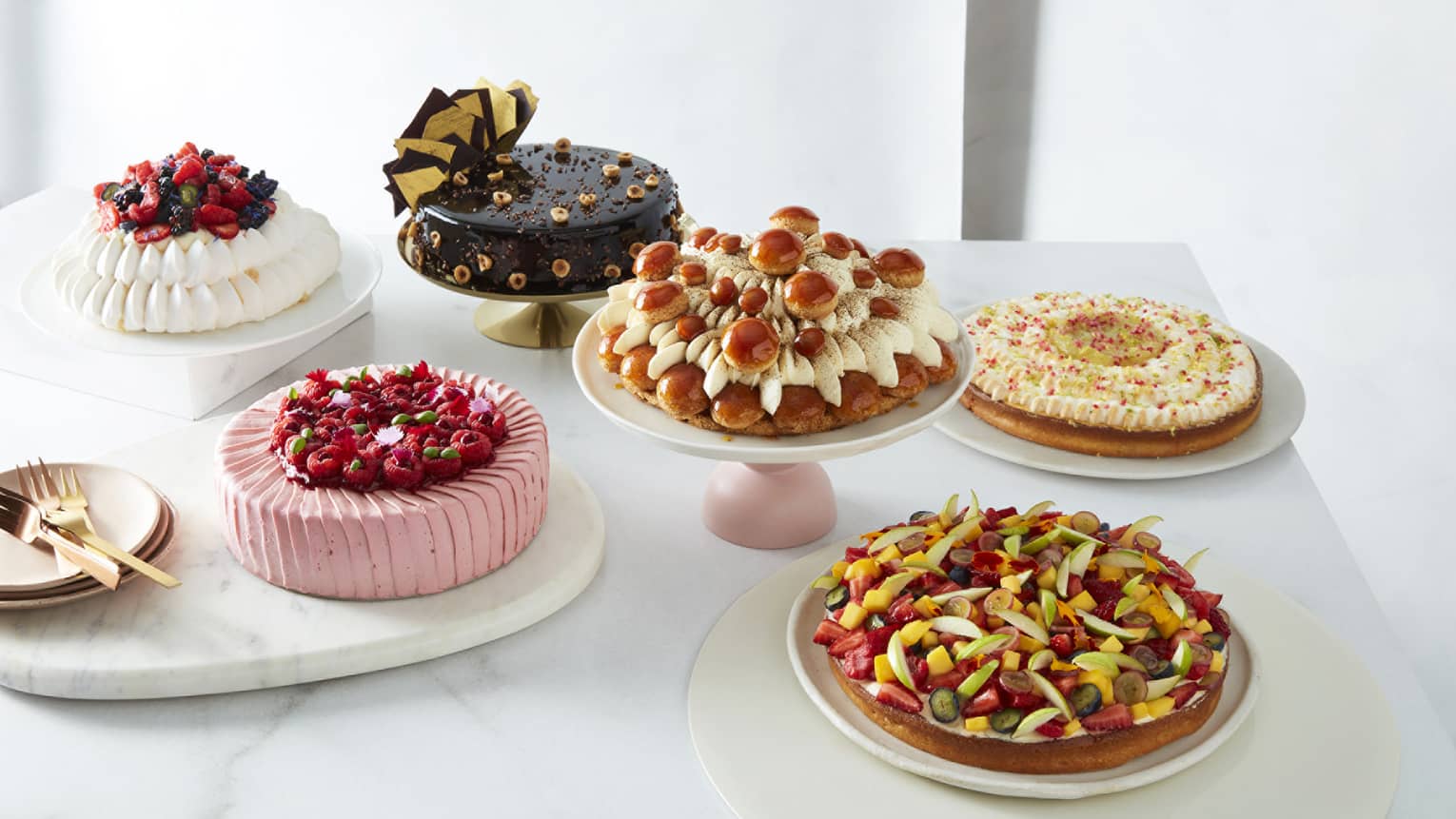 The Art of Cake Collection assorted cakes on white marble plates and stands