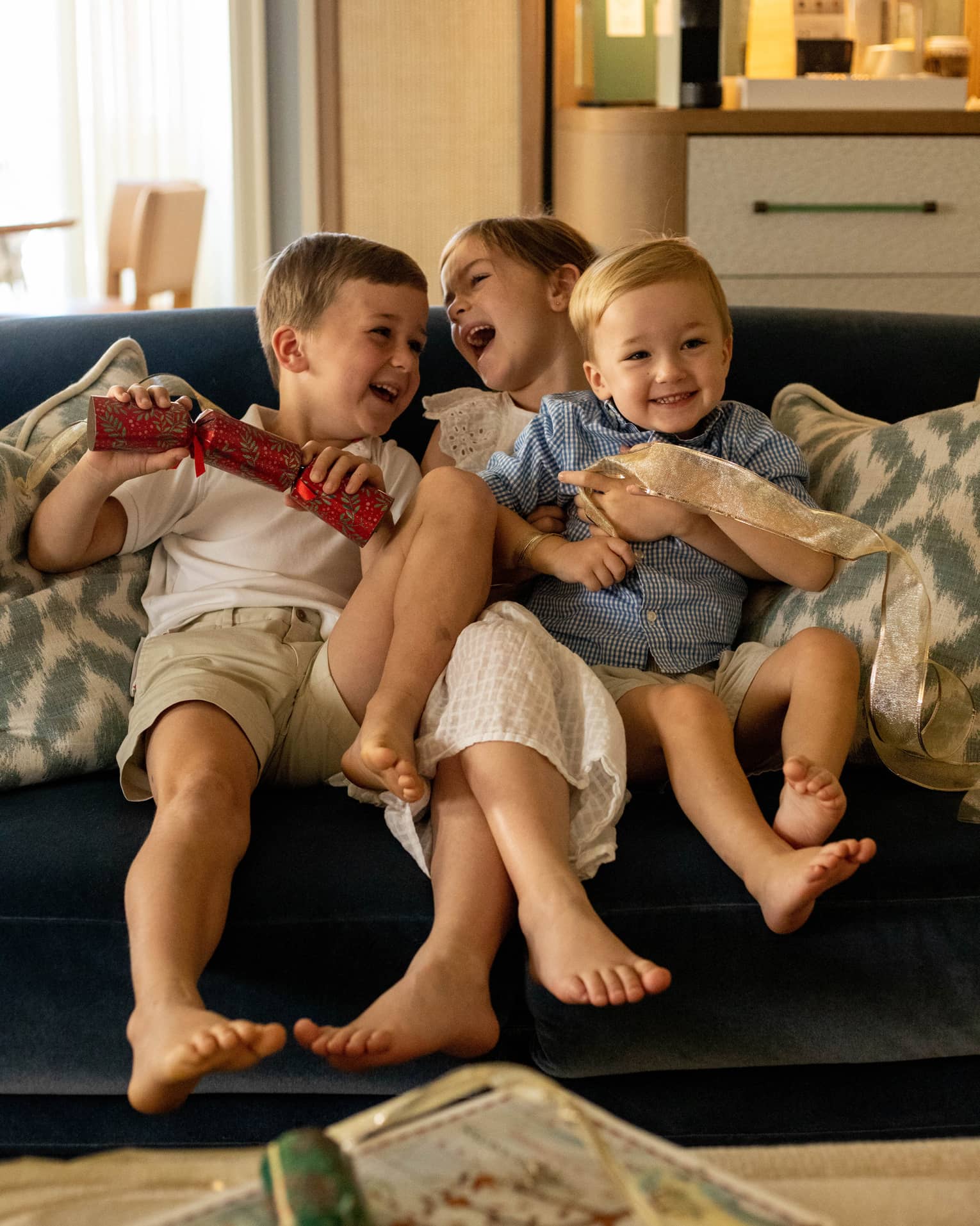 Three young children playing on a sofa.