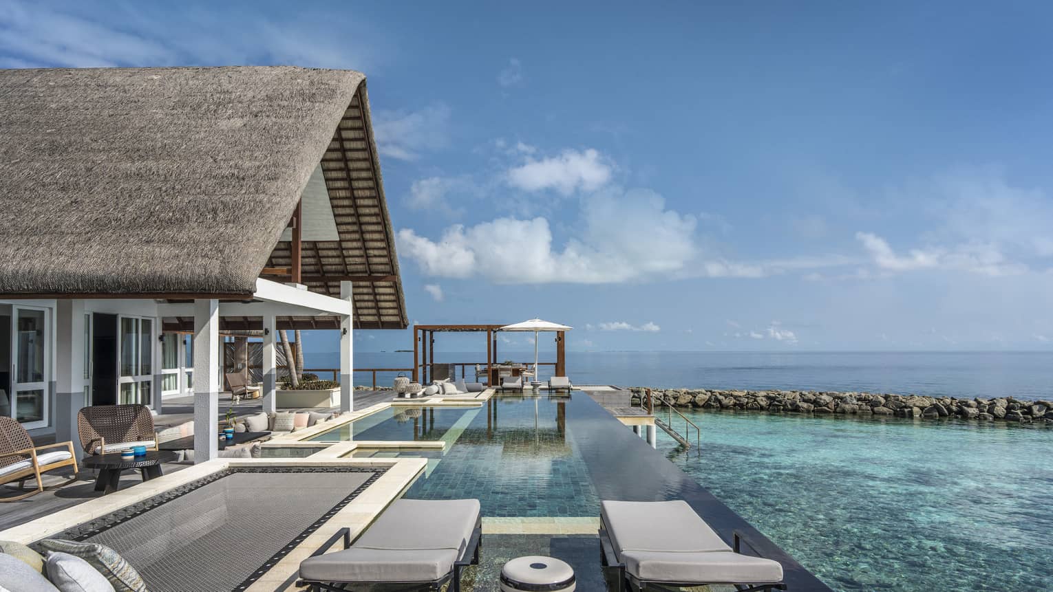 Private pool deck of overwater villa, with overwater lounge net and two chairs