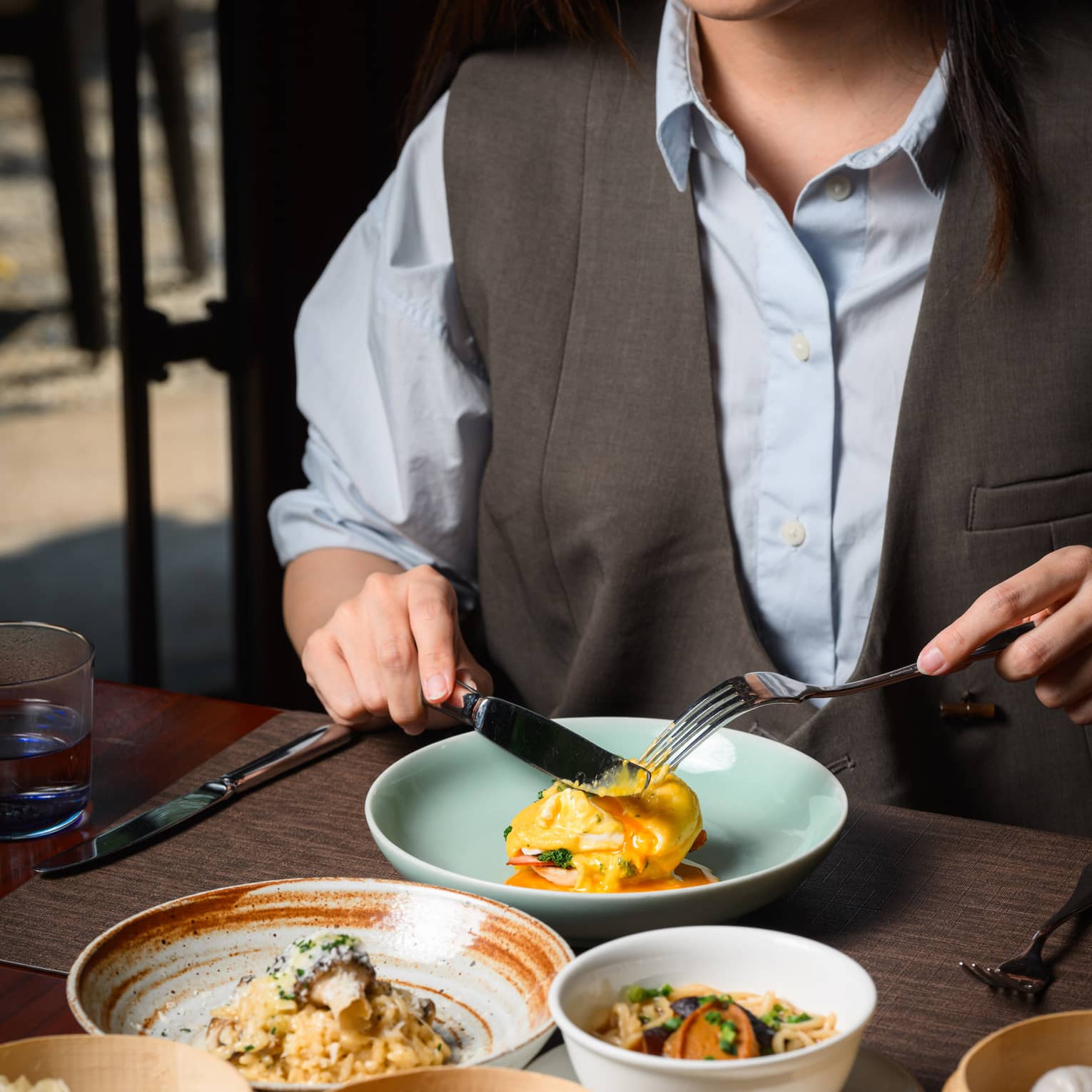 A guest enjoying an egg sandwich, with a mushroom risotto, a noodle dish and a medley of dim sum also laid out on the table.