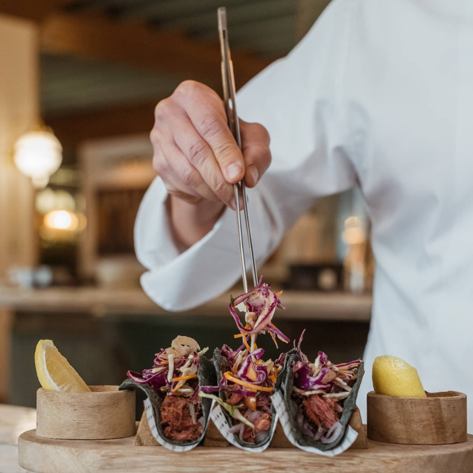 Chef arranging tacos on wooden platter