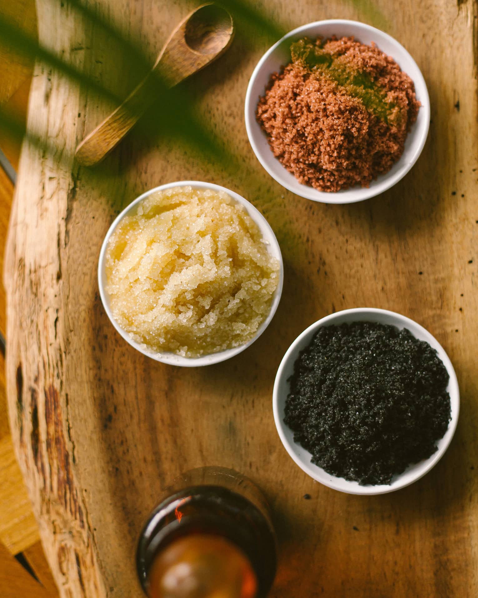 Aerial view of three dishes with salt scrubs on rustic wood platter