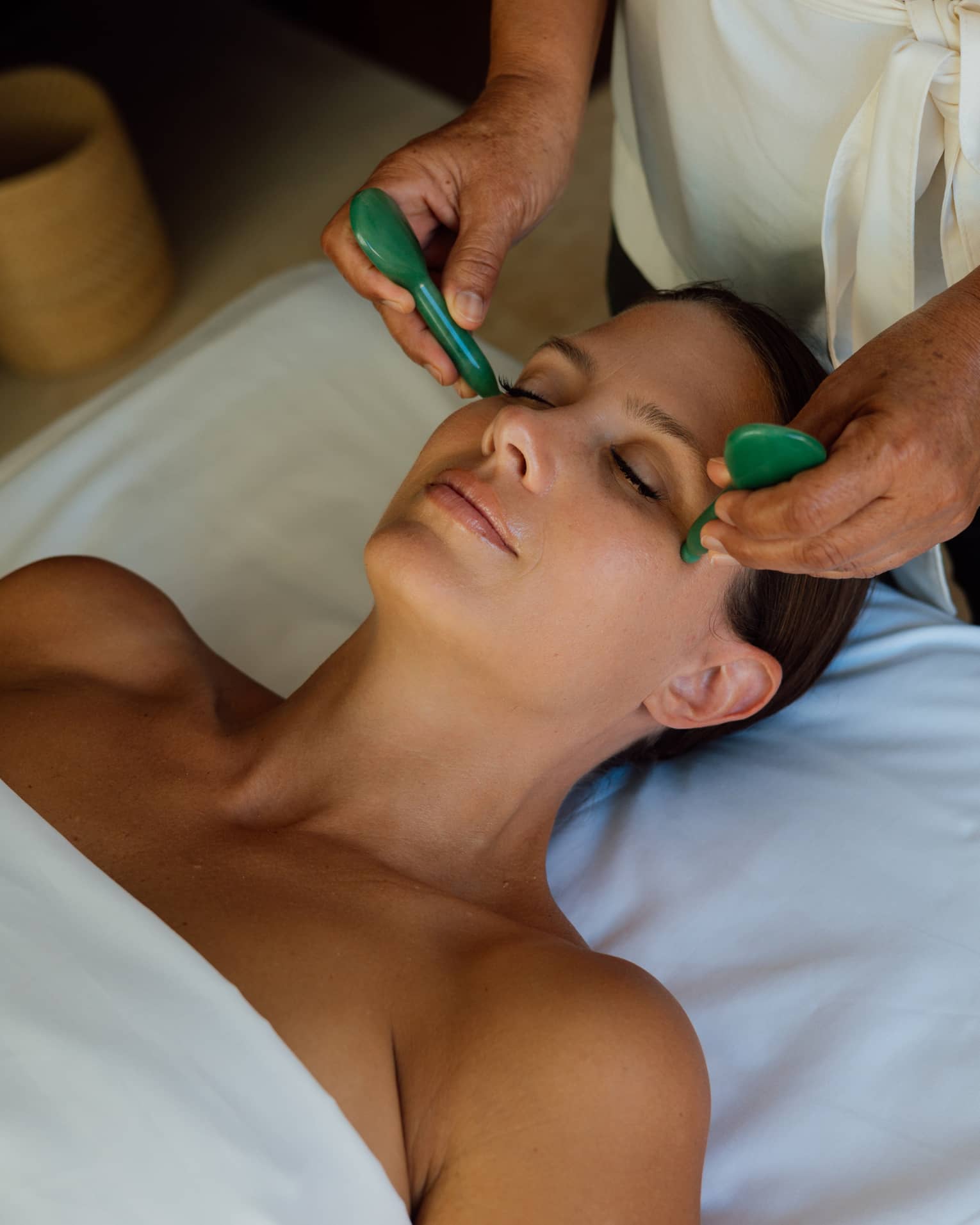 Guest getting a face massage while laying on a massage table.