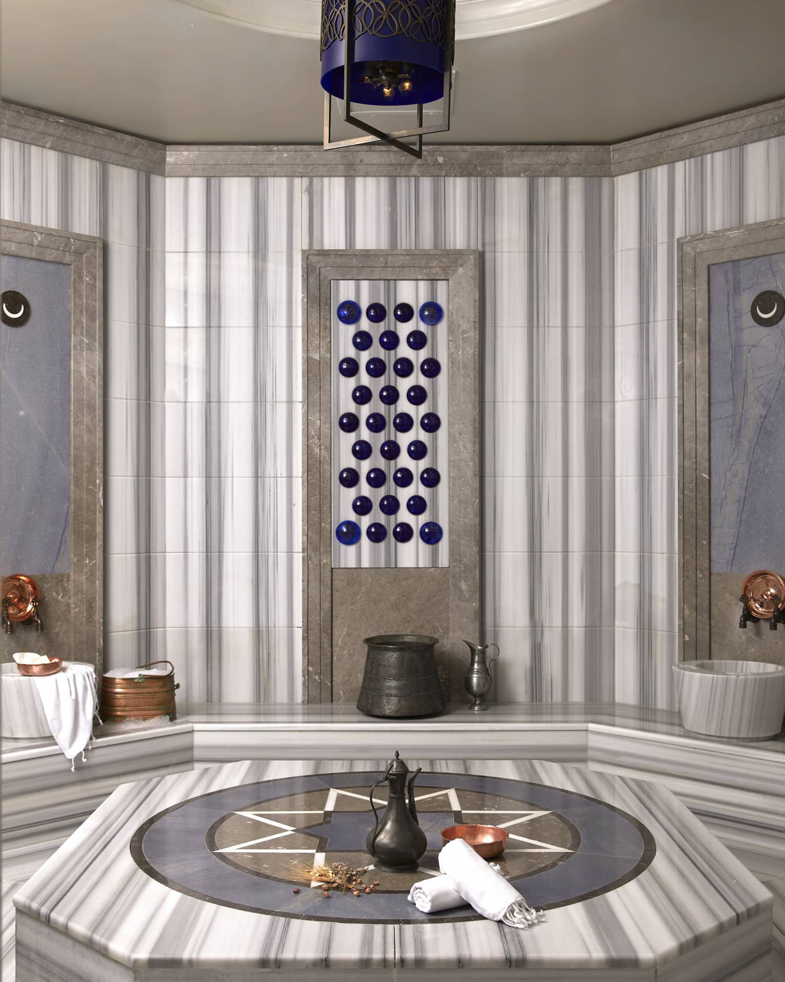 Rolled towels and kettle on marble bench in Turkish Hammam spa room