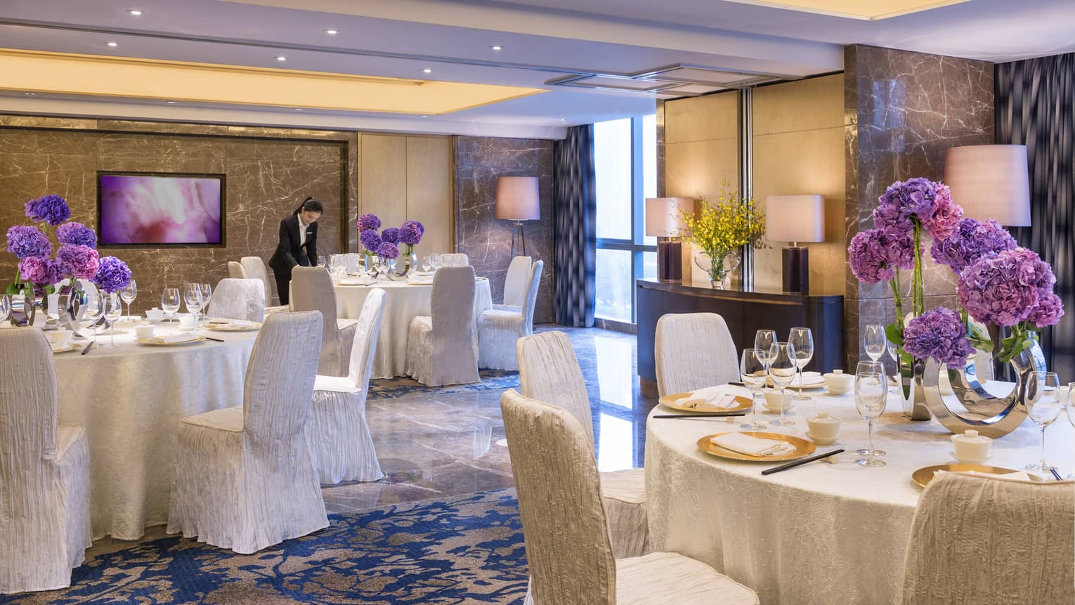 Orchid meeting room with round banquet tables with white linens, purple flowers