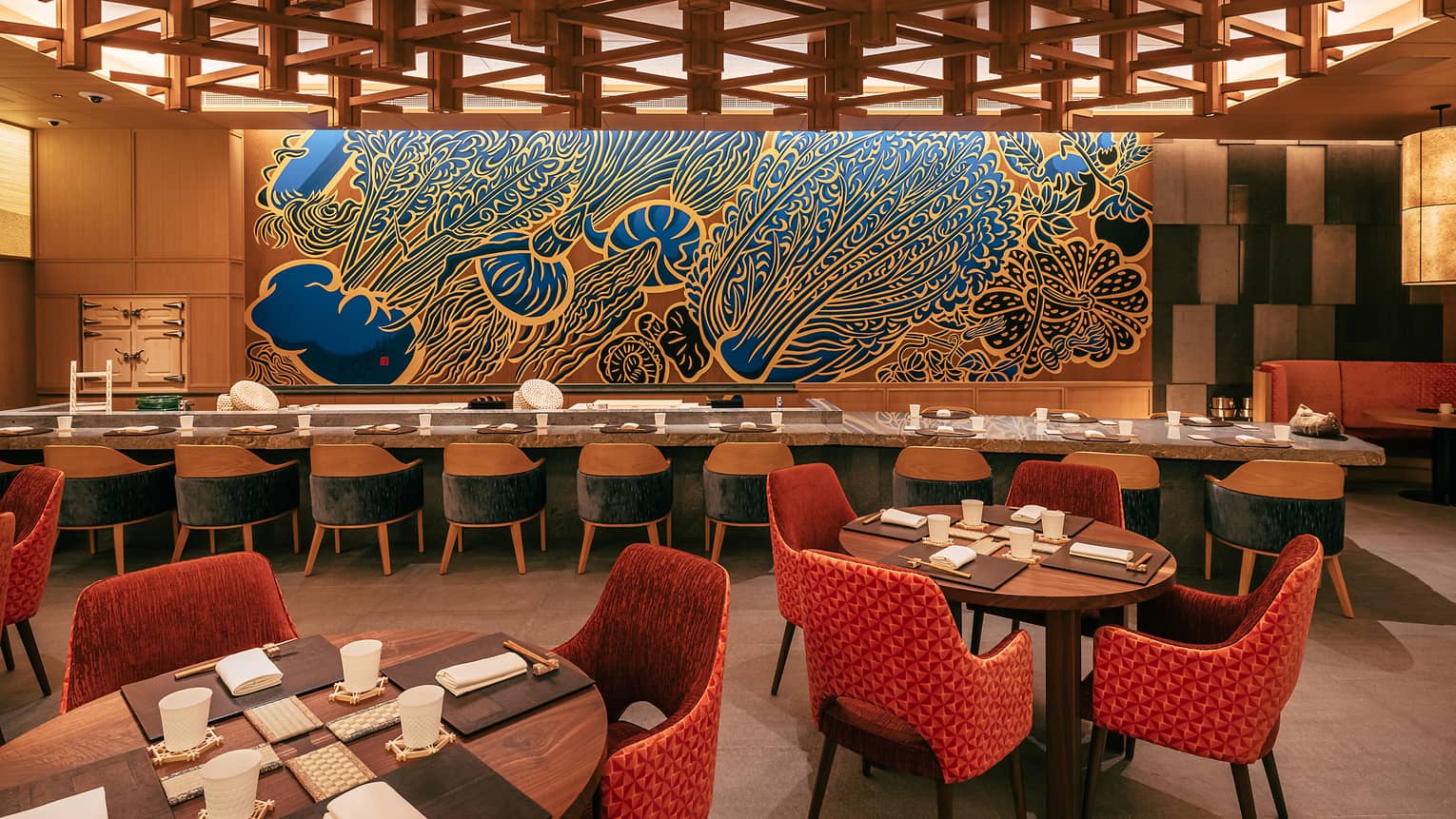 Restaurant dining room with a long rectangular communal table and various round tables set for four