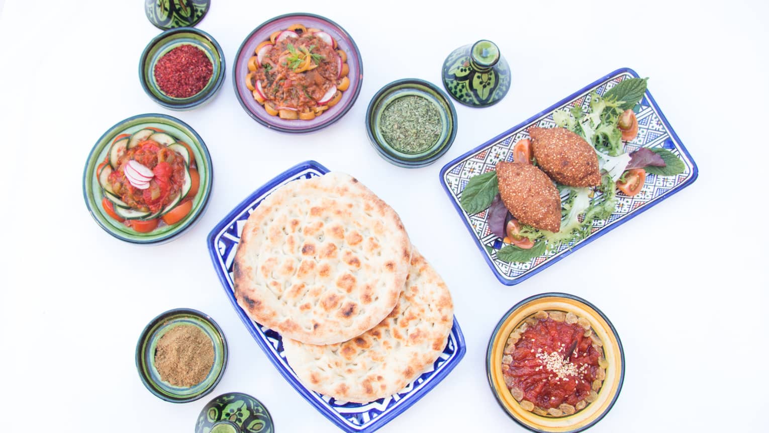 Looking down at Lebanese meze small appetizer dips, pita breads on table