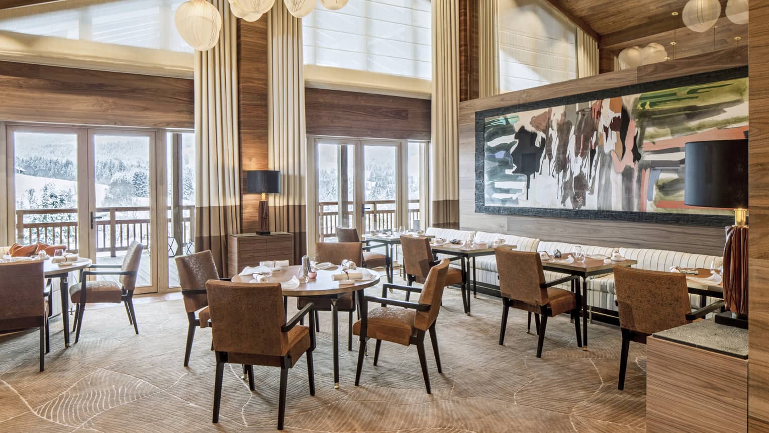 Le 1929 dining room, tables and chairs under gable roof, windows, modern lights, large painting