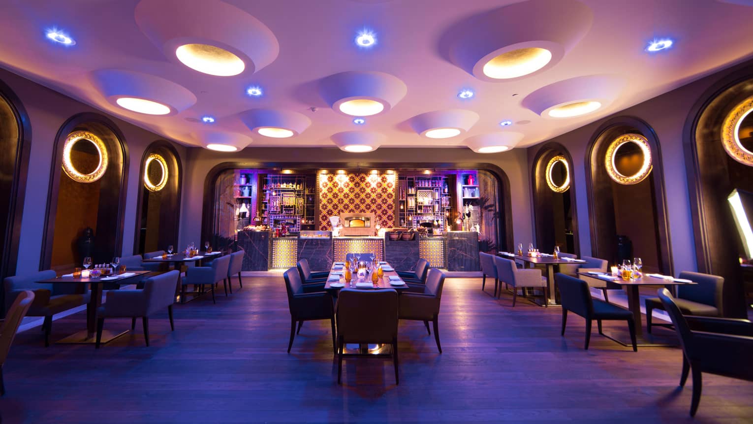 Candle-lit tables, chairs in Quattro dining room with large modern pot lights in white ceiling