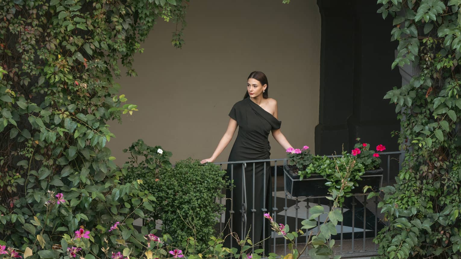 A hotel guest looks out upon a greenery-filled outdoor space.