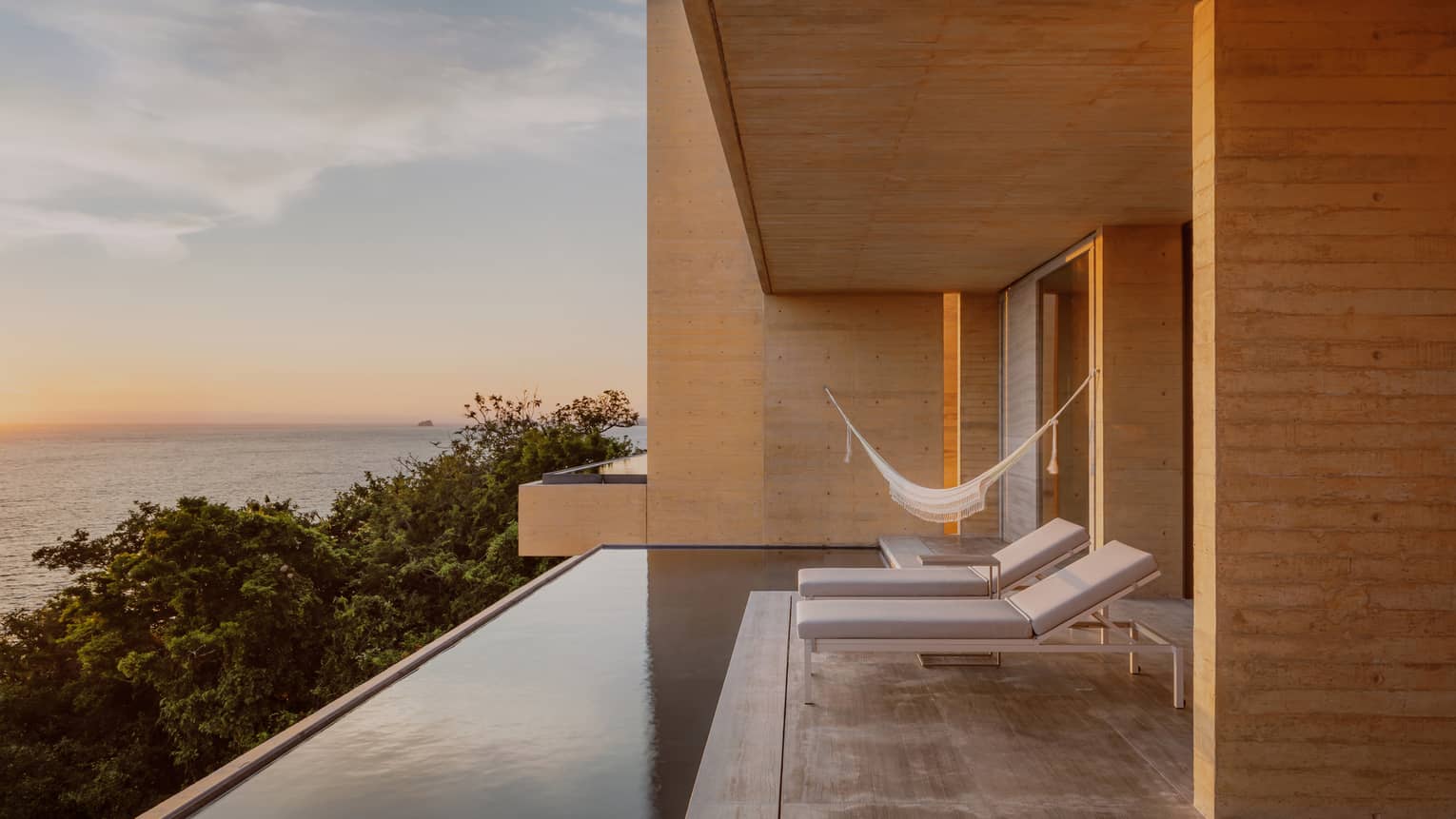 Resort suite private terrace with infinity pool, two lounge chairs, hammock and ocean view