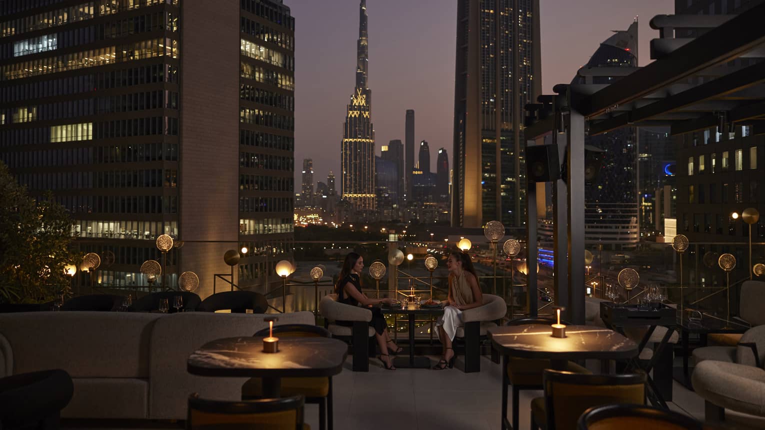 Nightime view of rooftop lounge with Dubai skyline in background
