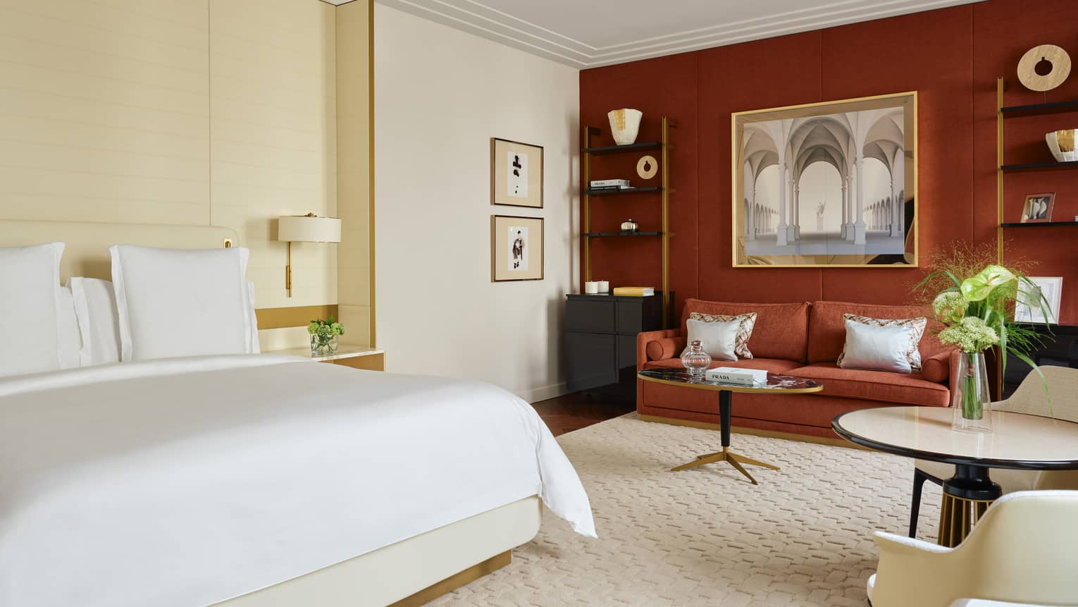 Hotel room with a king bed, off-white carpet and wall, and a red accent wall with matching coloured sofa