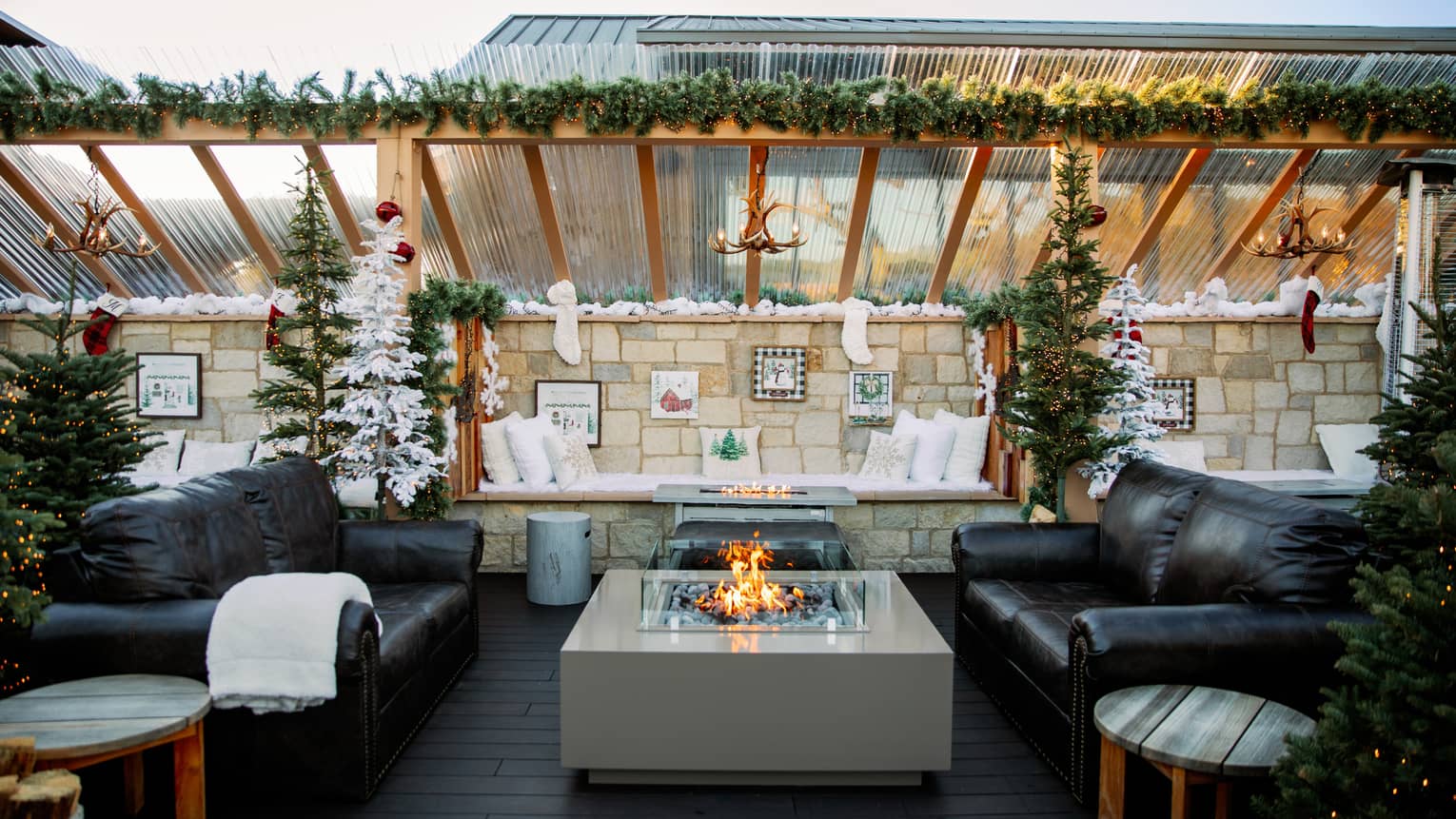 Outdoor terrace with two couches and a fire pit, and festive decorations.
