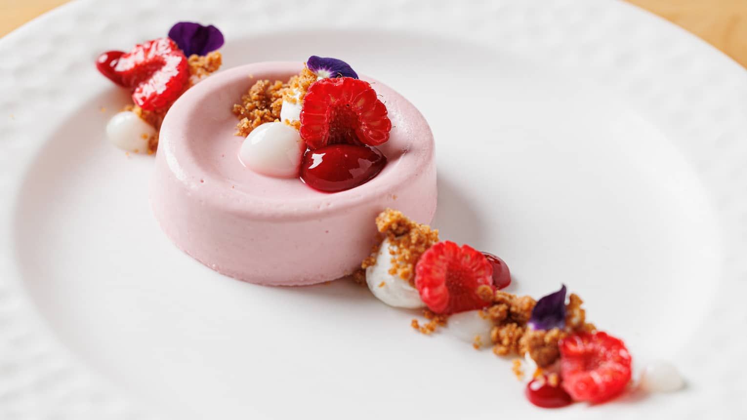 Berry panna cotta with whipped cream, gel�e dots and fresh mixed berries on white plate