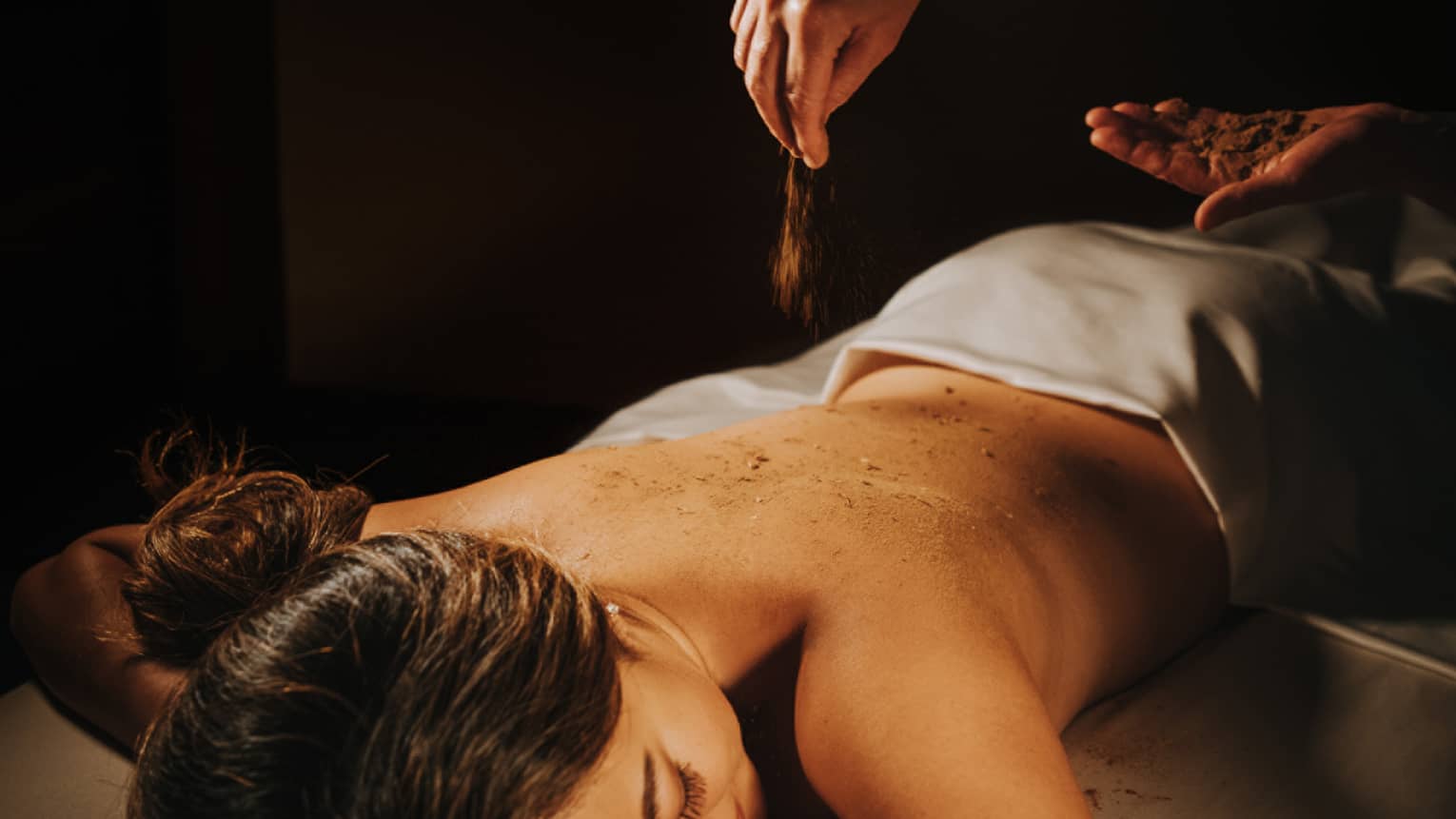 A guest in the 'Iliahi body cocoon, being moisturized with coconut oil and sprinkled with sandalwood powder