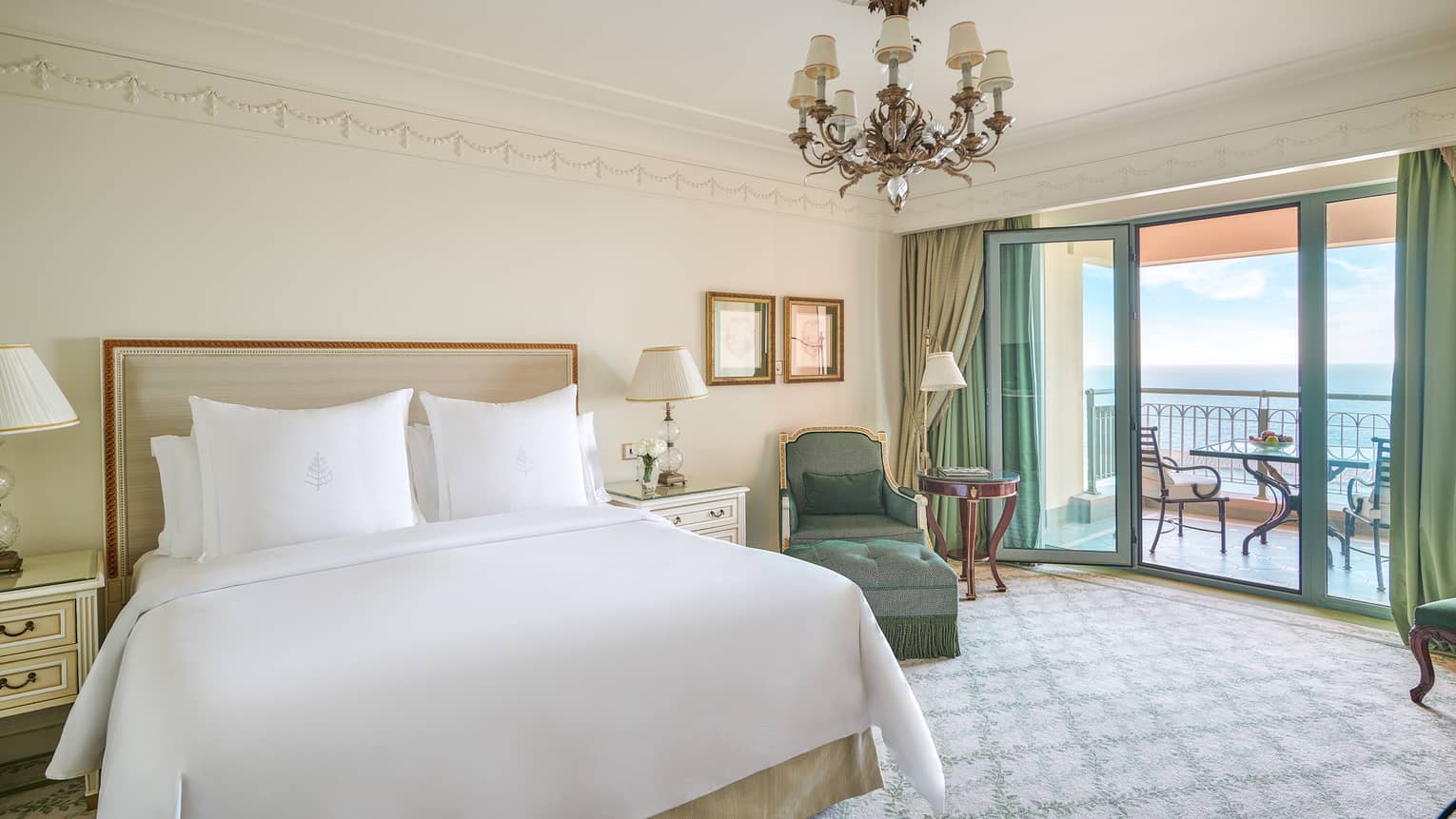 Sea View Suite bedroom with king bed, green chaise longue, glass door to veranda