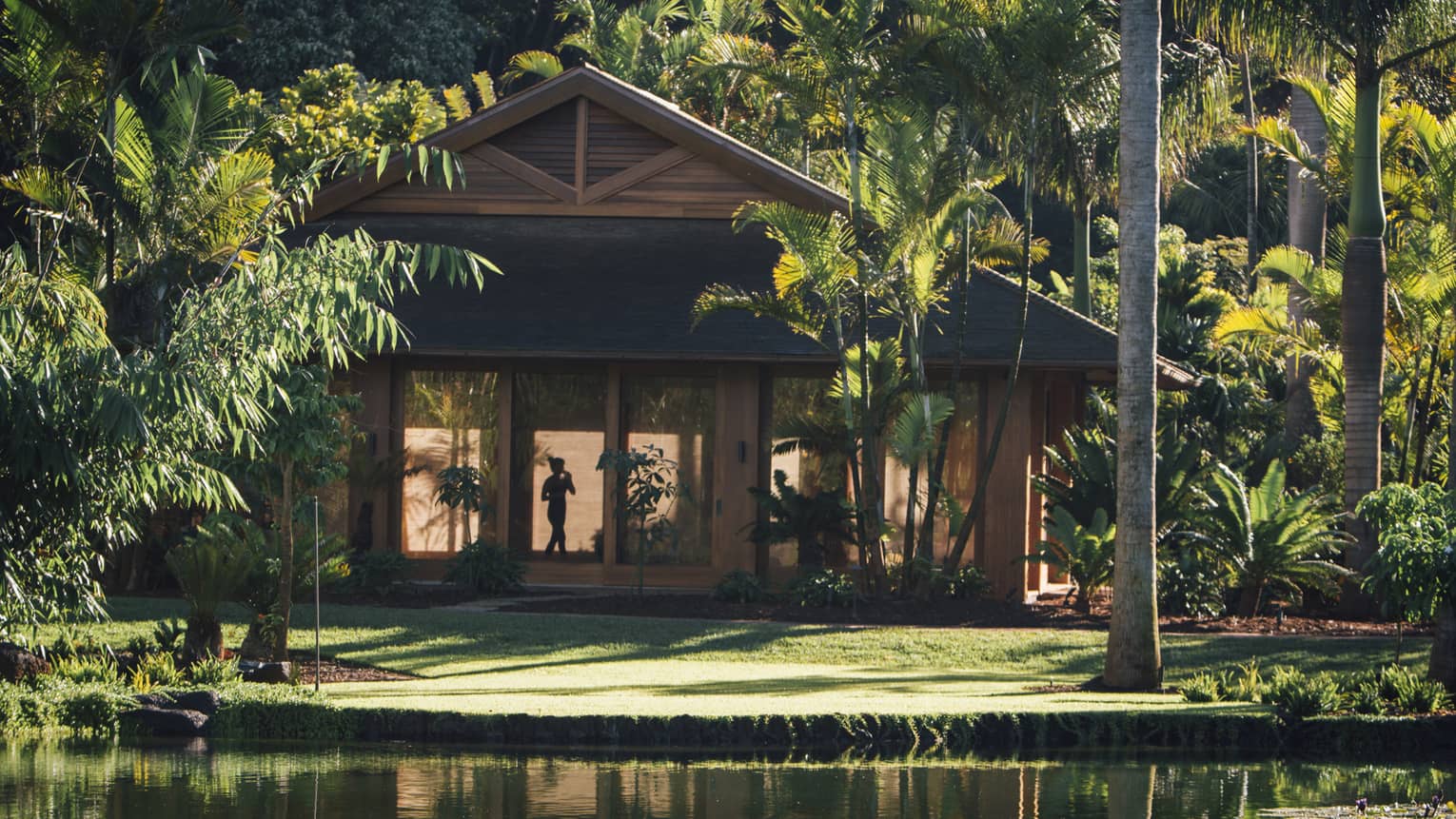 Exterior of a wooden tropical resort building by pond