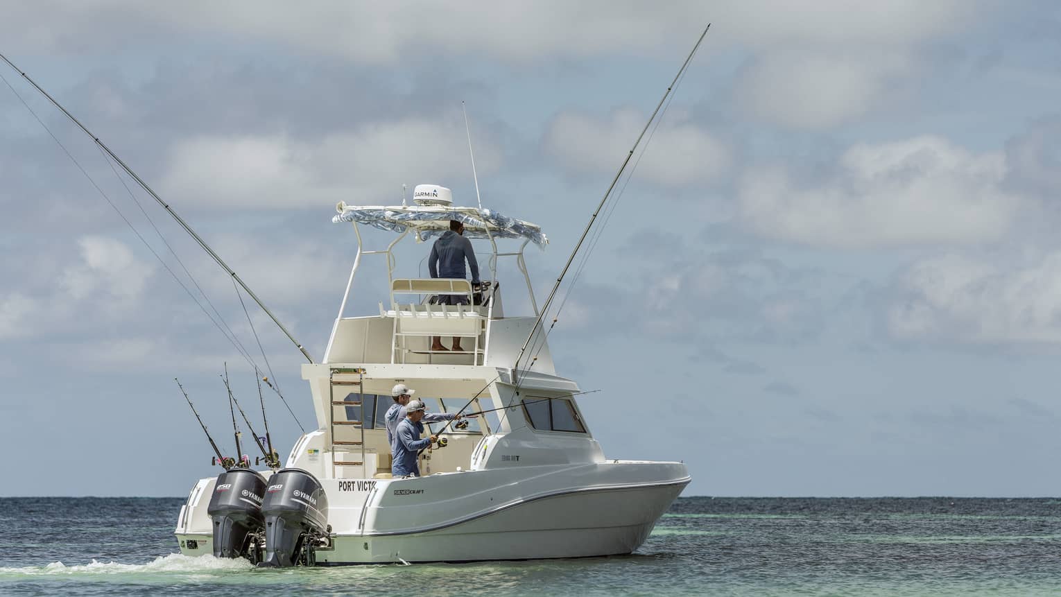 Two men fishing on the back of large white fishing boat